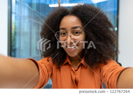 Webcam view, young woman taking selfie photo inside office at workplace. Female employee looking at camera smiling, using video call app on smartphone. Webcam view, young woman taking selfie photo inside office at workplace. Female employee looking at camera smiling, using video call app on smartphone. 122767264