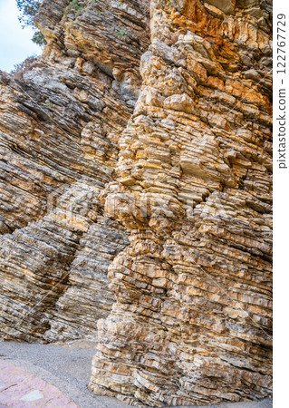 Layered rock texture in Budva, Montenegro. Sedimentary rocks with rugged surface of gray and brown. Natural formation of layers and cracks, geological structure. 122767729