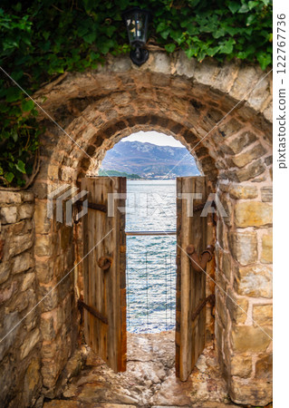 Old street in old town of Budva without people in winter time with small gate in the end to sea coast, Montenegro.  122767736