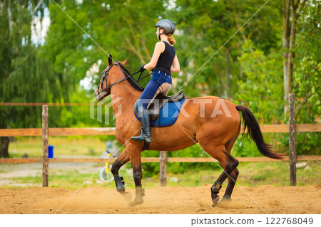 Jockey girl doing horse riding on countryside meadow 122768049