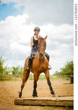 Jockey girl doing horse riding on countryside meadow 122768052
