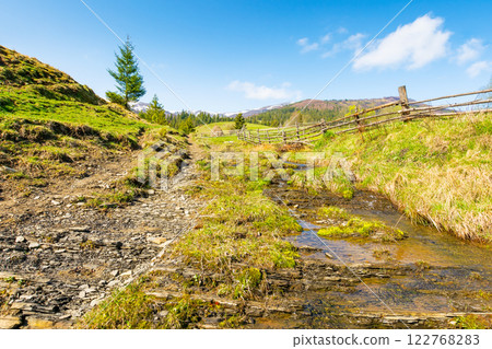 countryside scenery of ukraine in spring. outdoor adventure. sunny morning. mountainous rural landscape with grassy field on a hill behind fence. brook in the valley. idyllic weather countryside scenery of ukraine in spring. outdoor adventure. sunny morning. mountainous rural landscape with grassy field on a hill behind fence. brook in the valley. idyllic weather 122768283