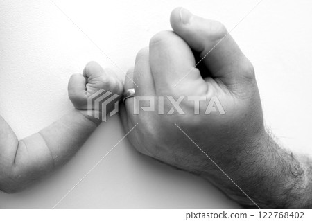 Two hands: man and child. Father and son touching fists. Dad and newborn son boys holding hands together. Little and big fists of father and son. Black and white professional photo.  122768402