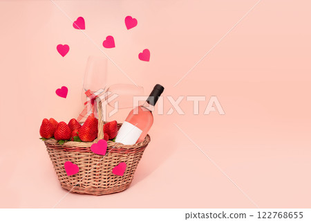 Romantic strawberry and rose wine basket with two glasses and hearts on pink background with copy space. 122768655