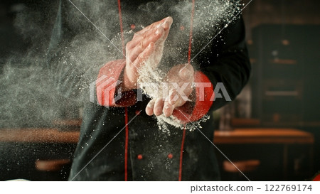 Freeze motion of baker clapping his hands with flour exploding. 122769174