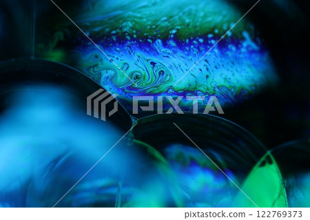 Bright rainbow reflection of liquid on black background, blue surface, surrealistic background, fantastic surface movement, beautiful science  122769373