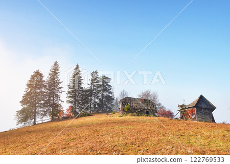 Sunrise above the high mountain foggy valley with old wooden houses on a hill in a mountain forest Sunrise above the high mountain foggy valley with old wooden houses on a hill in a mountain forest 122769533