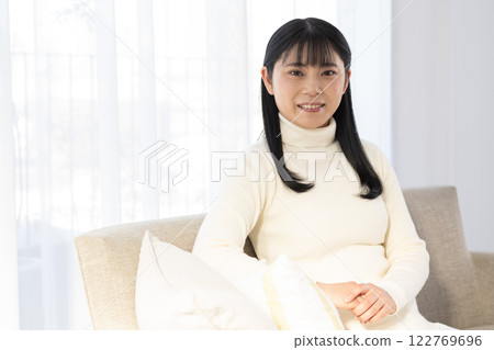 Woman sitting on sofa and looking at camera Woman sitting on sofa and looking at camera 122769696