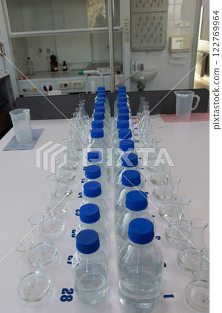Laboratory equipment. Laboratory storage bottles with blue polypropylene cap on white table. 122769964