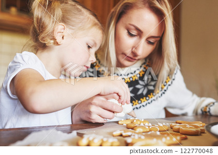 Mom and daughter decorate the Christmas cookie with white sugar 122770048
