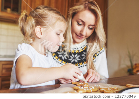 Mom and daughter decorate the Christmas cookie with white sugar Mom and daughter decorate the Christmas cookie with white sugar 122770049