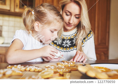 Mom and daughter decorate the Christmas cookie with white sugar Mom and daughter decorate the Christmas cookie with white sugar 122770050