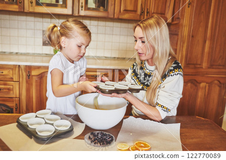 A little beautiful girl is preparing cupcakes 122770089