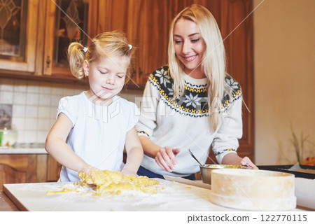 Happy smiling mom in the kitchen bakes cookies with her daughter. 122770115