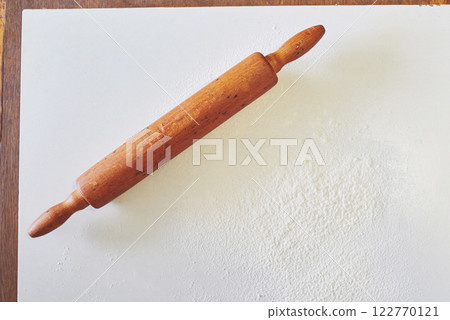 Wooden rolling pin with white wheat flour on the table. top view 122770121