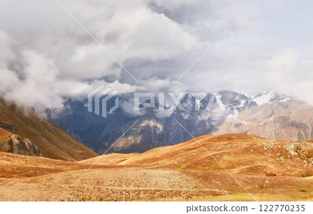 Fantastic snow-capped mountains in the beautiful cumulus clouds. Main Caucasian Ridge. Type Mount Ushba Meyer, Georgia 122770235