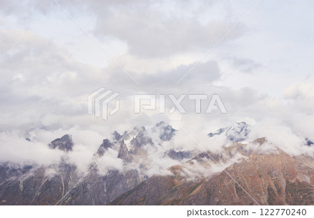 Fantastic snow-capped mountains in the beautiful cumulus clouds. Main Caucasian Ridge. Type Mount Ushba Meyer, Georgia 122770240