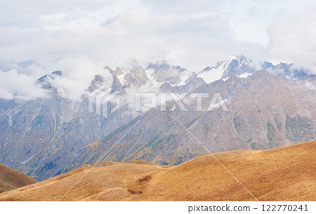 Fantastic snow-capped mountains in the beautiful cumulus clouds. Main Caucasian Ridge. Type Mount Ushba Meyer, Georgia 122770241