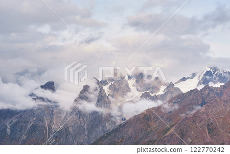 Fantastic snow-capped mountains in the beautiful cumulus clouds. Main Caucasian Ridge. Type Mount Ushba Meyer, Georgia 122770242