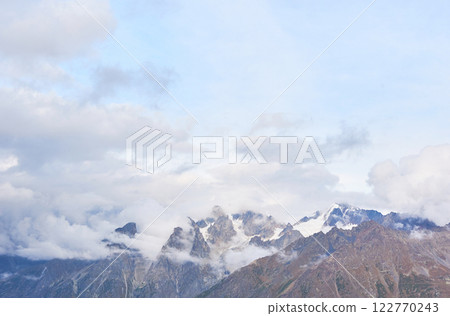 Fantastic snow-capped mountains in the beautiful cumulus clouds. Main Caucasian Ridge. Type Mount Ushba Meyer, Georgia 122770243