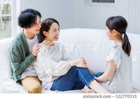 Smiling parent and child sitting on the sofa in the living room 122770313