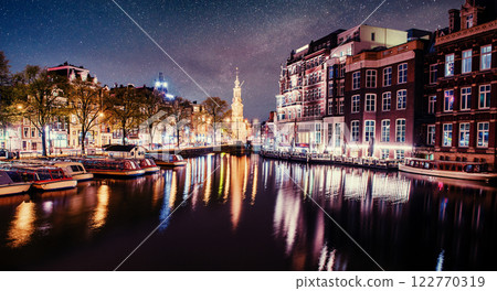Beautiful night in Amsterdam. Night illumination of buildings and boats near the water in the canal. Beautiful night in Amsterdam. Night illumination of buildings and boats near the water in the canal. 122770319