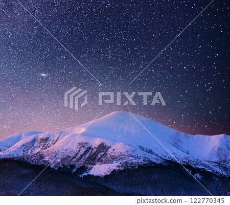 Beautiful winter landscape in the Carpathian mountains. Vibrant night sky with stars and nebula and galaxy. Deep sky astrophoto 122770345