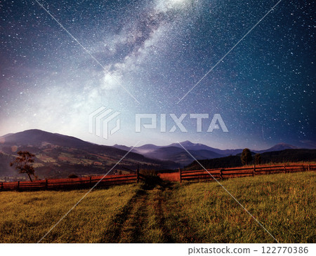 Mountain summer landscape. High grass and vibrant night sky with stars and nebula and galaxy. Deep sky astrophoto Mountain summer landscape. High grass and vibrant night sky with stars and nebula and galaxy. Deep sky astrophoto 122770386