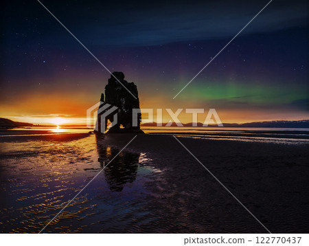 starry sky and northern lights in a spectacular rock in the sea on the Northern coast of Iceland. Legends say it is a petrified troll 122770437