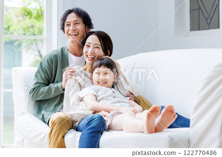 微笑的父母和孩子坐在客廳的沙發上 微笑的父母和孩子坐在客廳的沙發上 122770486