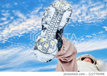 Snow boot sole with cleats, snowy tread pattern against . cloudy sky. Snow boot sole with cleats, snowy tread pattern against . cloudy sky. 122770496