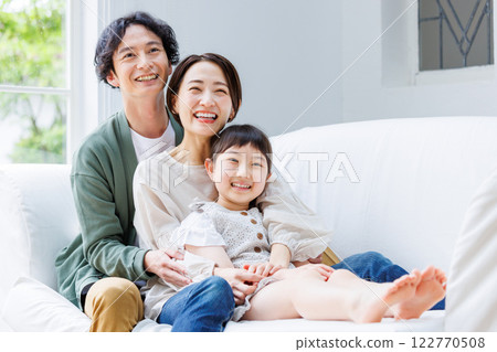 微笑的父母和孩子坐在客廳的沙發上 微笑的父母和孩子坐在客廳的沙發上 122770508