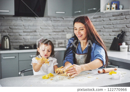 A beautiful daughter with her mother bakes New Year's greetings. Merry Christmas A beautiful daughter with her mother bakes New Year's greetings. Merry Christmas 122770966
