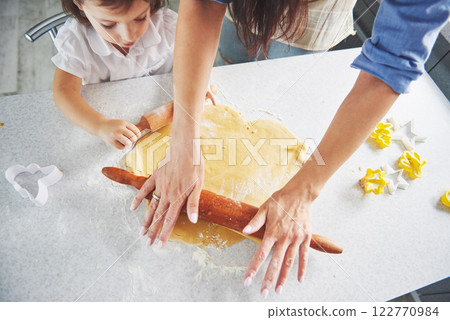 Happy family preparation holiday food concept. Family cooking Christmas cookies. Hands of mother and daughter preparing the dough on the table. Happy family in making cookies at home Happy family preparation holiday food concept. Family cooking Christmas cookies. Hands of mother and daughter preparing the dough on the table. Happy family in making cookies at home 122770984