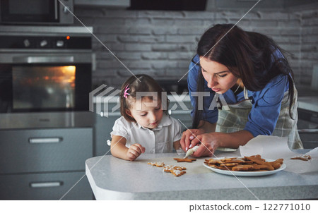Happy family in the kitchen. Holiday food concept. Mother and daughter decorate cookies. Happy family in making homemade pastry. Homemade food and little helper 122771010