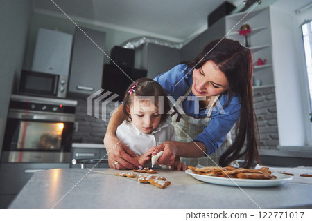 Happy family in the kitchen. Holiday food concept. Mother and daughter decorate cookies. Happy family in making homemade pastry. Homemade food and little helper 122771017