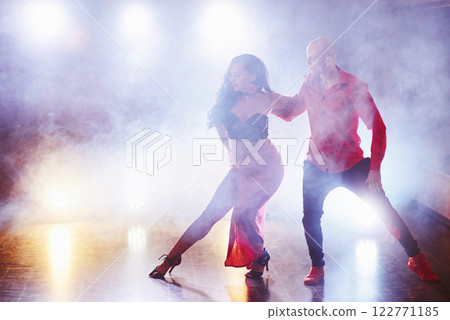 Skillful dancers performing in the dark room under the concert light and smoke. Sensual couple performing an artistic and emotional contemporary dance 122771185