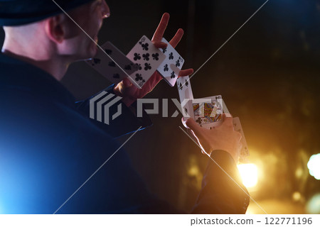 Magician showing trick with playing cards. Magic or dexterity, circus, gambling. Prestidigitator in dark room with fog 122771196