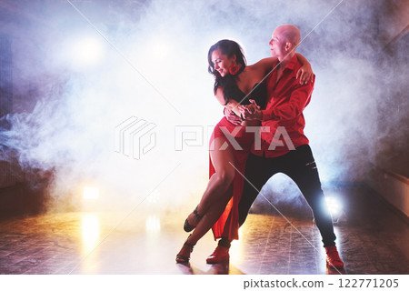 Skillful dancers performing in the dark room under the concert light and smoke. Sensual couple performing an artistic and emotional contemporary dance Skillful dancers performing in the dark room under the concert light and smoke. Sensual couple performing an artistic and emotional contemporary dance 122771205