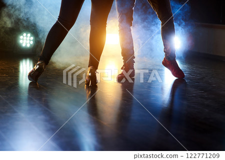 Skillful dancers performing in the dark room under the concert light and smoke. Beautiful womanish and masculine legs in active dance Skillful dancers performing in the dark room under the concert light and smoke. Beautiful womanish and masculine legs in active dance 122771209