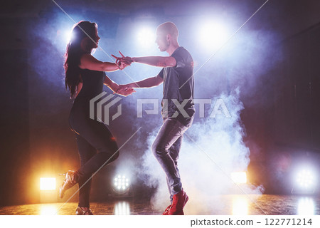 Skillful dancers performing in the dark room under the concert light and smoke. Sensual couple performing an artistic and emotional contemporary dance 122771214