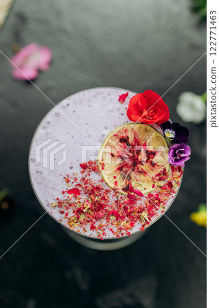 Elegant purple cocktail in a martini glass, garnished with dried lime, petals, and edible flowers Elegant purple cocktail in a martini glass, garnished with dried lime, petals, and edible flowers 122771463