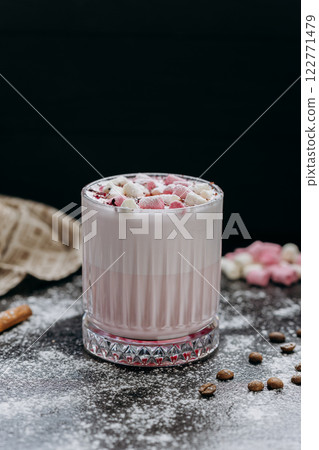 Cup of pink hot chocolate with marshmallows and powdered sugar on a rustic dark background 122771479