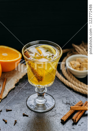 Aromatic spiced tea with orange and cinnamon in an elegant glass, creating a cozy and warm ambiance 122771486