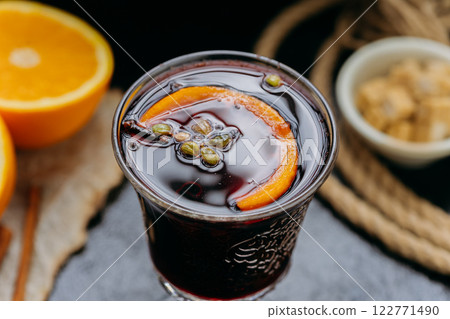 Mulled wine with orange and spices in elegant glass, creating a cozy and festive winter atmosphere Mulled wine with orange and spices in elegant glass, creating a cozy and festive winter atmosphere 122771490