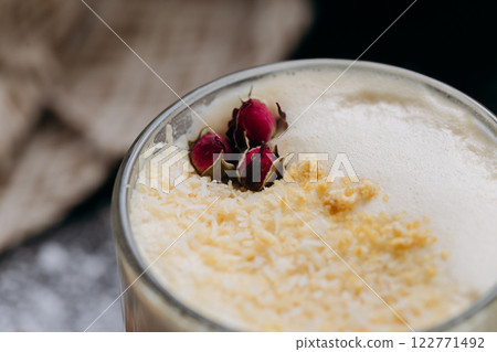 Creamy latte with coconut flakes and dried rose garnish, served in a glass with a velvety frothy top Creamy latte with coconut flakes and dried rose garnish, served in a glass with a velvety frothy top 122771492