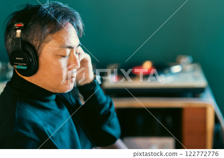 Middle-aged man enjoying music with wired headphones 122772776
