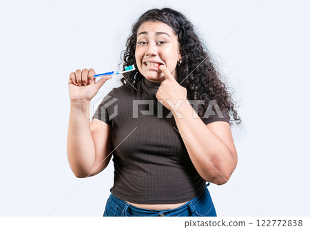 Girl suffering from gum pain holding toothbrush. Young woman with gingivitis holding toothbrush isolated. People holding toothbrush with gum problem 122772838
