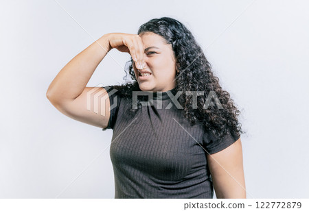 Young woman covering her nose from a bad smell isolated. Displeased girl holding her nose isolated. Disgust people covering nose 122772879