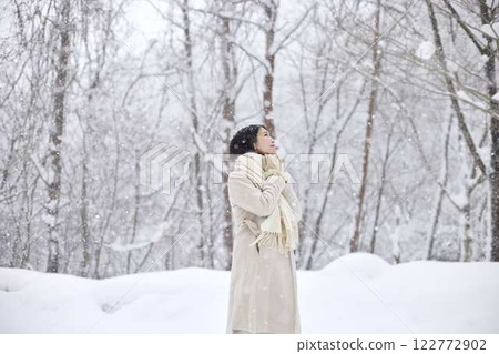 A Japanese woman wearing a scarf standing in a snowy winter country 122772902